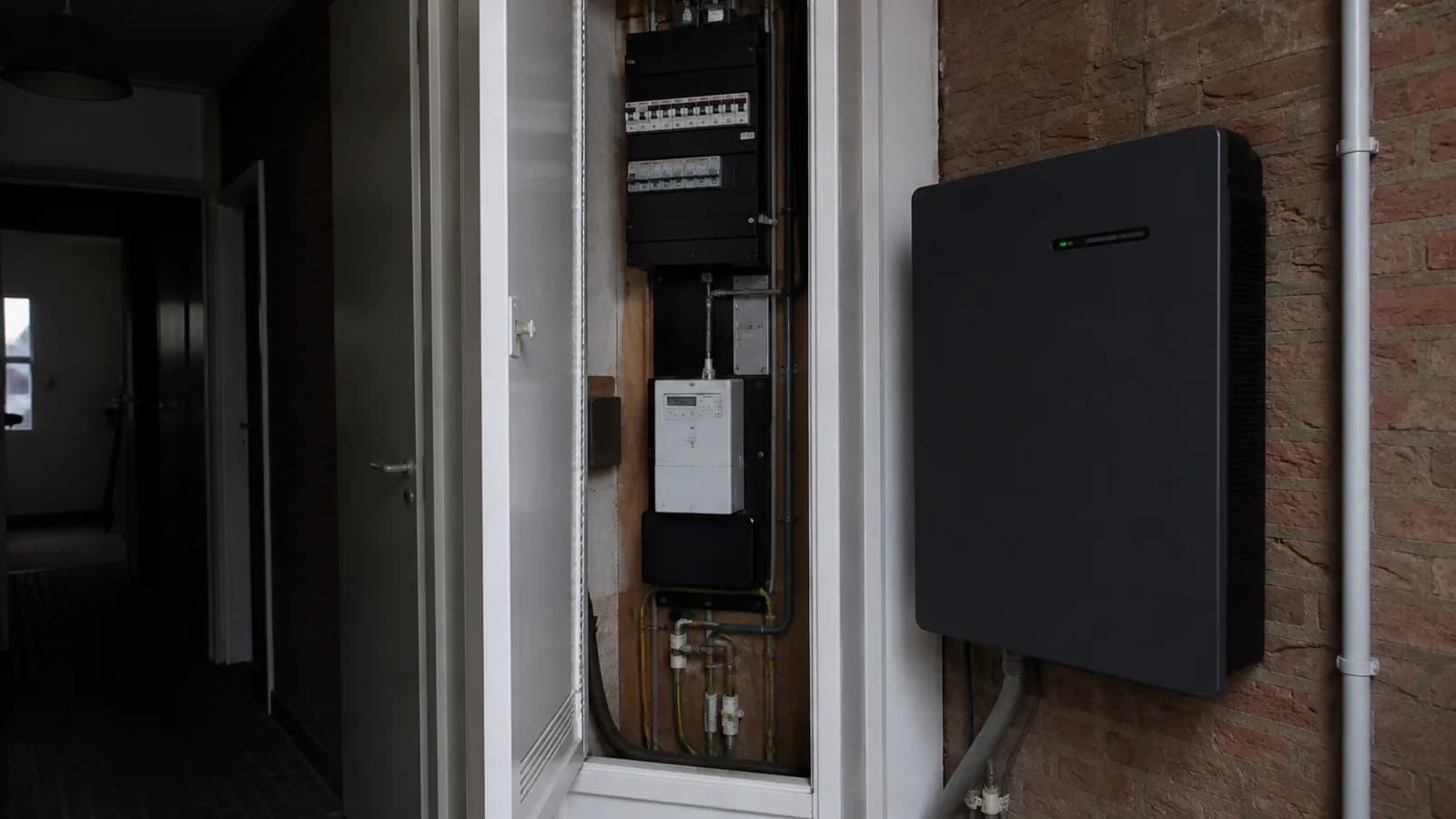 Open meterkast naast een muuraccu in een donkere gang