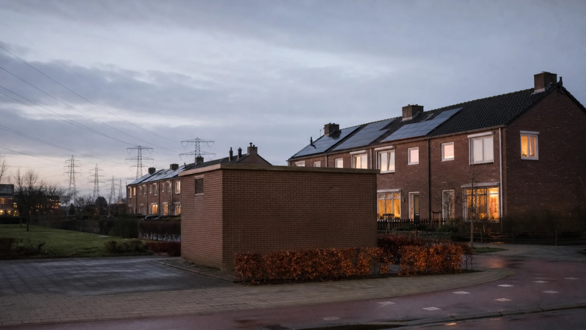 Woonwijk met trafohuisje en hoogspanningsmasten in de schemering