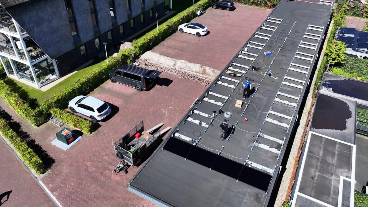 Monteurs leggen rails en panelen op een plat dak