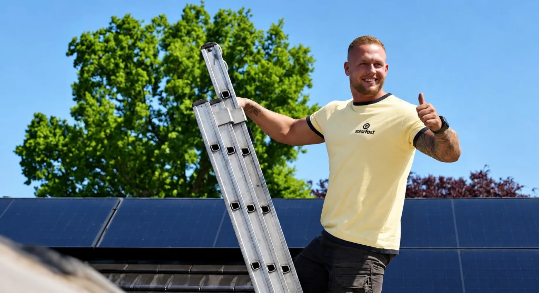 SolarFast monteur in geel shirt op een ladder bij zonnepanelen