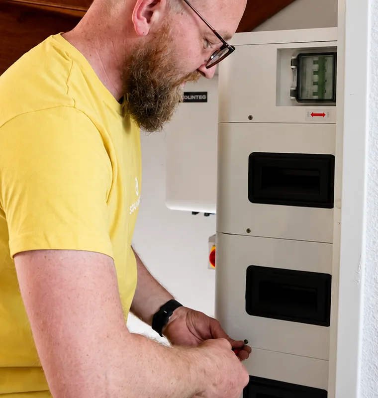 SolarFast installer working on a home battery by the meter cupboard