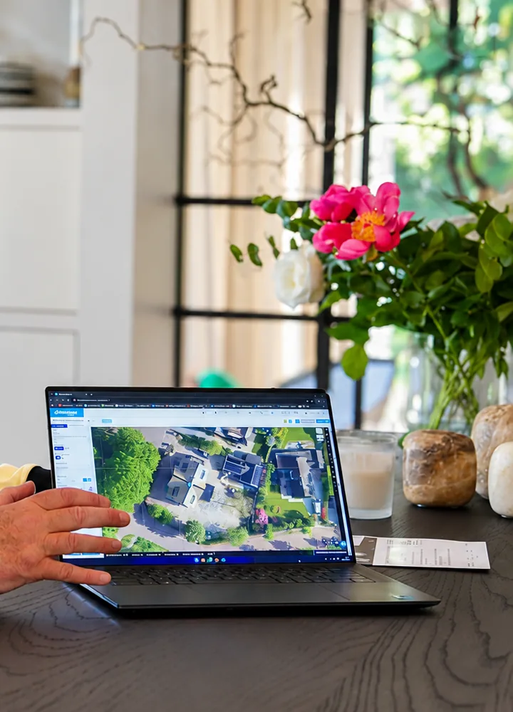 SolarFast advisor showing a customer's roof on a laptop, with flowers on the table