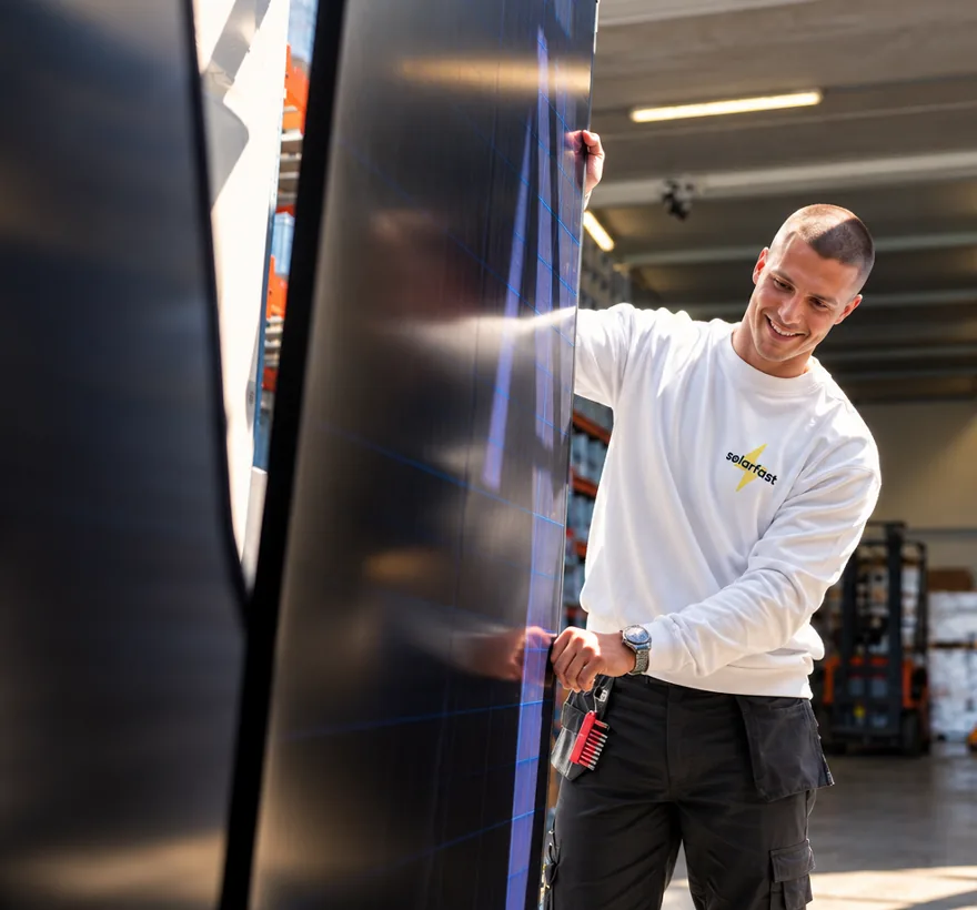 SolarFast installer holding a solar panel in the warehouse