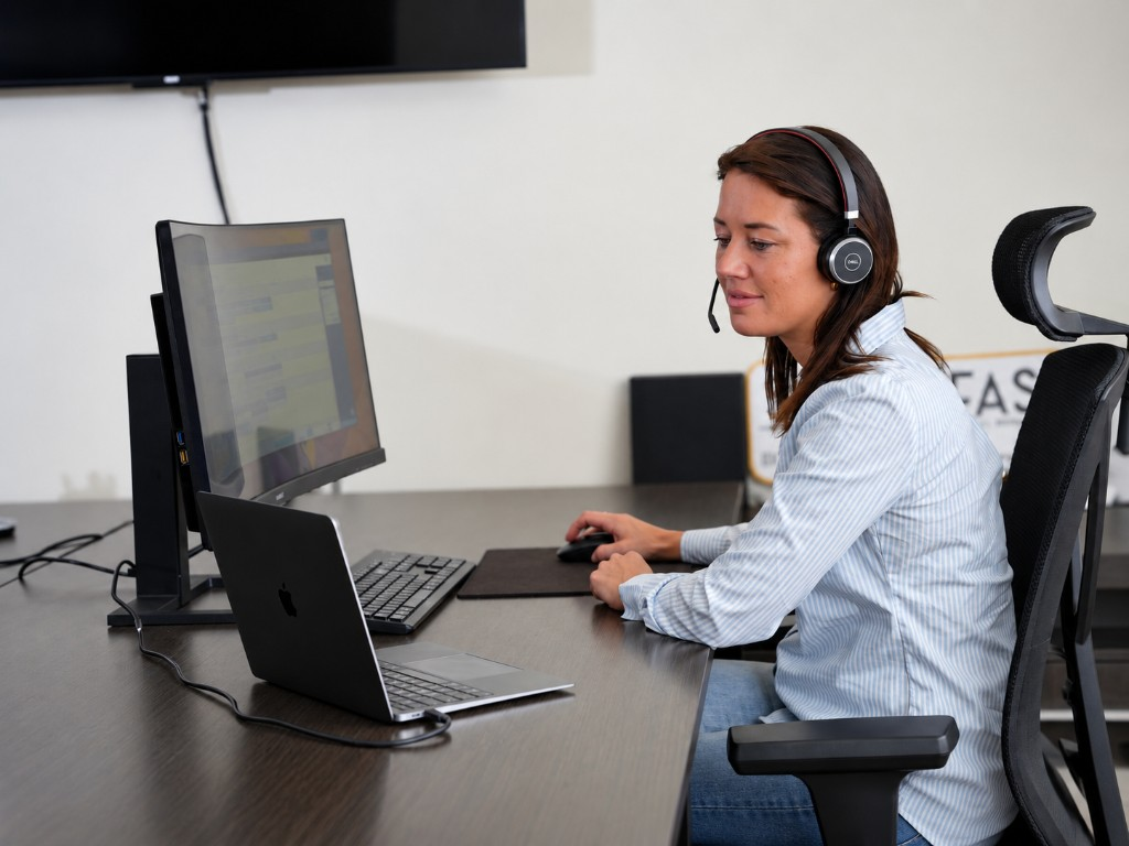 Collega van SolarFast luistert met headset tijdens een gesprek aan haar bureau